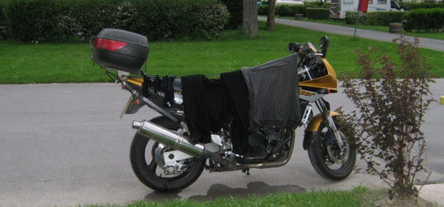 a motorcycle with clothes drying on a bungee stretched from the handlebar to the rack
